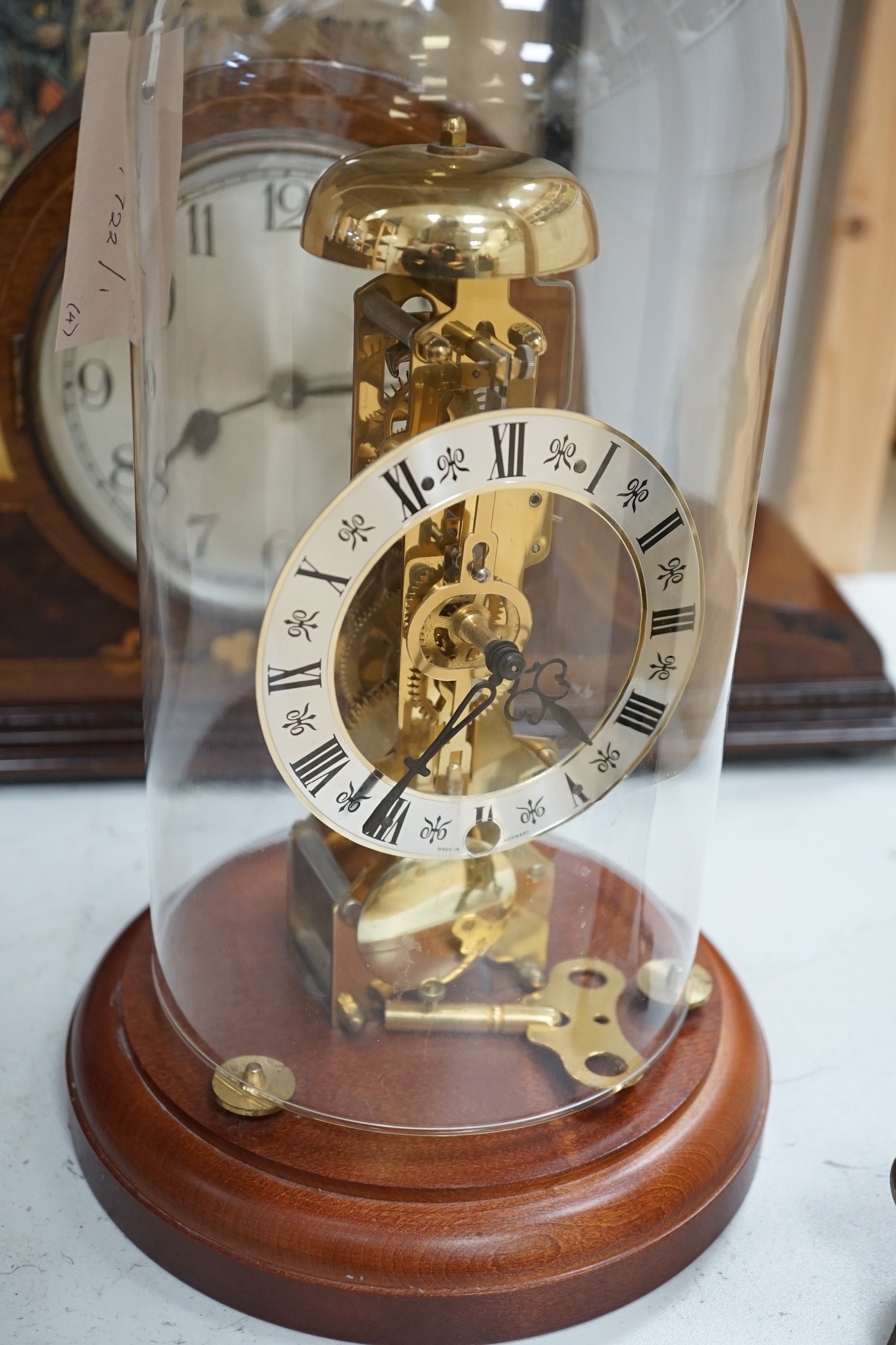 An early 20th century inlaid mahogany mantel clock, a skeleton clock under glass dome, a brass desk calendar and a 19th century French framed print, skeleton clock and dome 32cms high